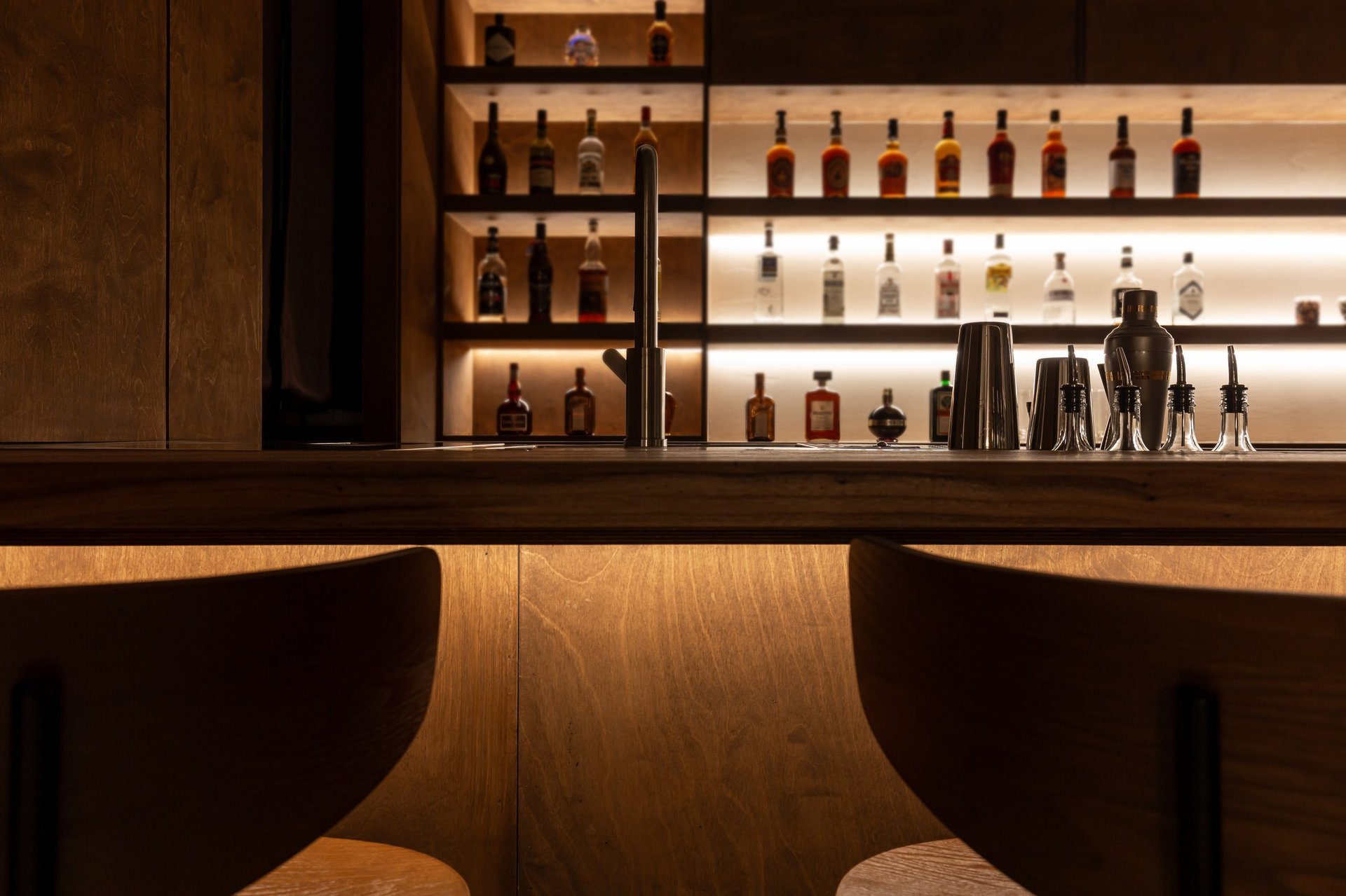Moody luxury bar interior with warm low golden lighting, atmospheric nightlife setting